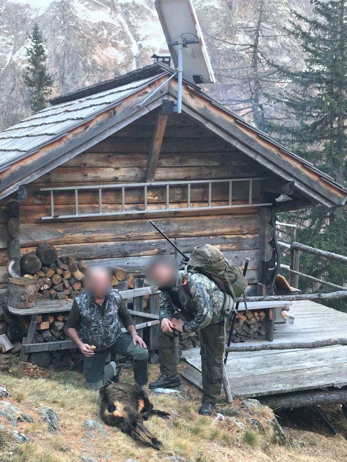 Two hunters with a chamois outside a wooden mountain hut, Austria